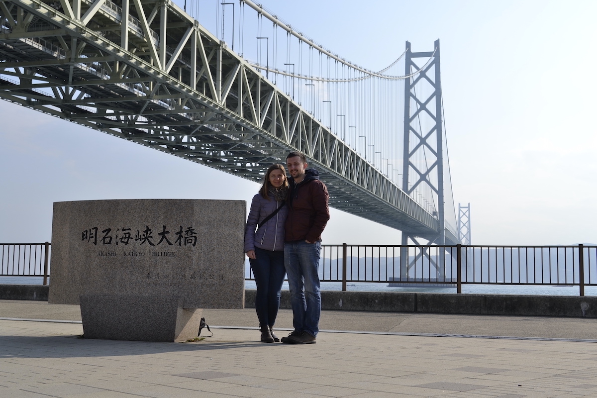 two people sitting in front of the akashi kaikyo bridge