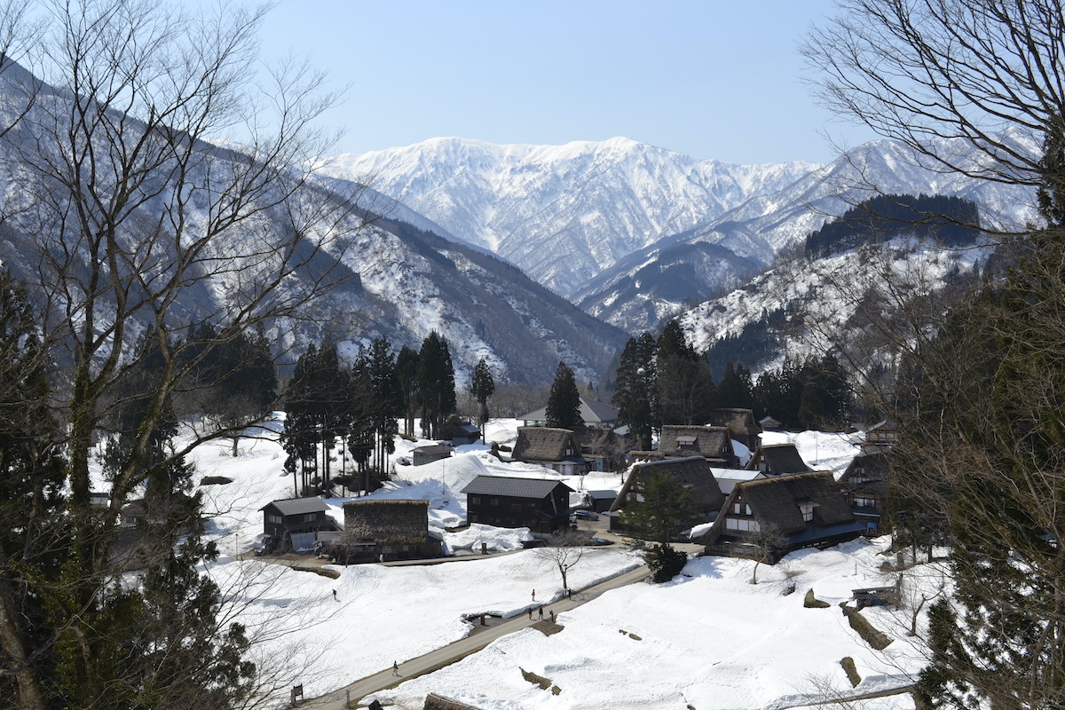 Snowy fields with traditional houses and a mountainous backdrop